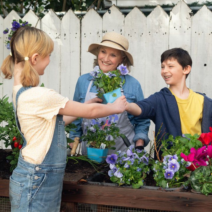 Two grandkids gardening with their grandma who's better protected by TruStage Insurance.