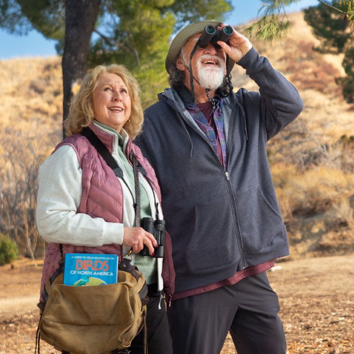 An older couple better protected by TruStage Insurance are birdwatching in the hills