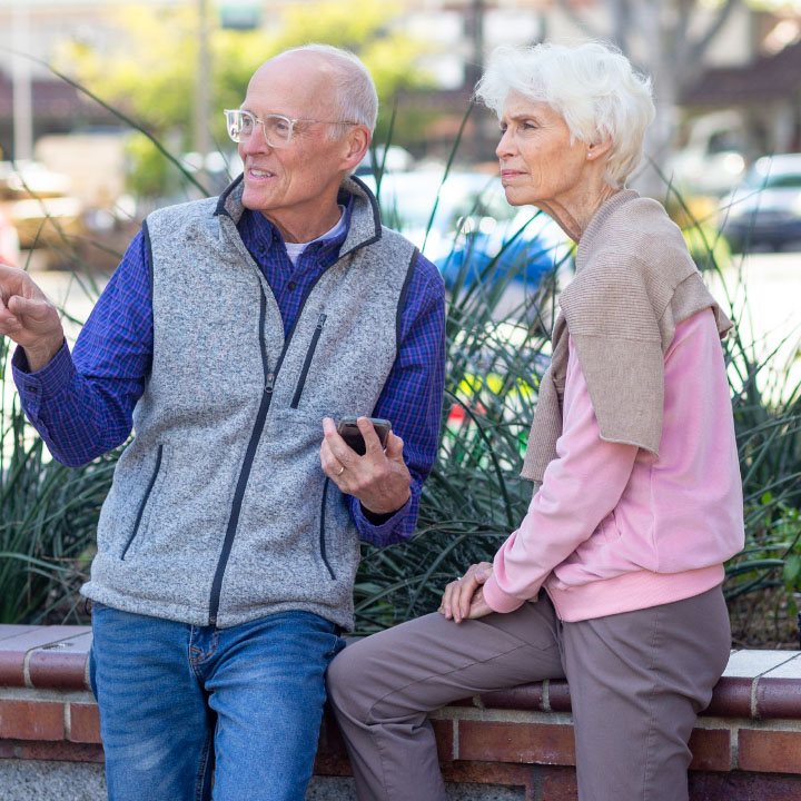 An elderly couple enjoy a break from their outdoor walk are better protected in retirement by a TruStage Annuity.
