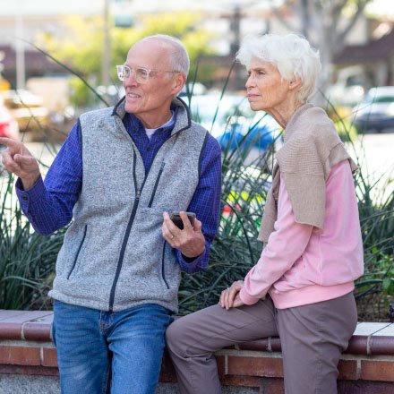 An elderly couple enjoy a break from their outdoor walk are better protected in retirement by a TruStage Annuity.