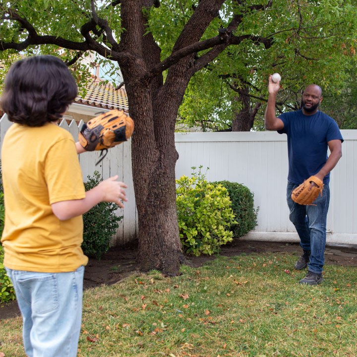 Dad and son play catch in their backyard are better protected by TruStage Life Insurance.