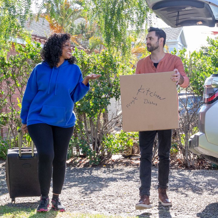 A man and woman moving boxes into their home