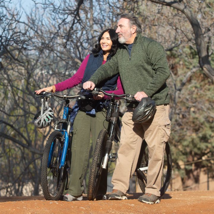 A man and woman stand beside their bicycles, discussing accidental death and dismemberment insurance.