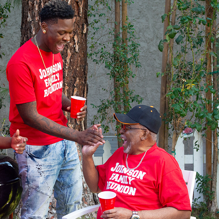 A grandfather and grandson talking to each other at a family reunion