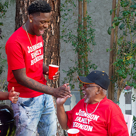 A grandfather and grandson talking to each other at a family reunion
