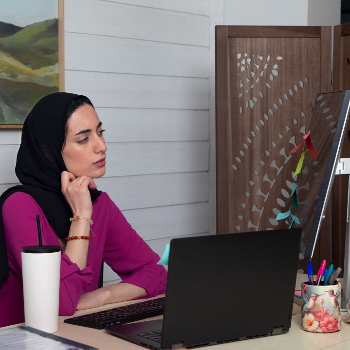 A woman sits at her desk researching term life insurance on her laptop.