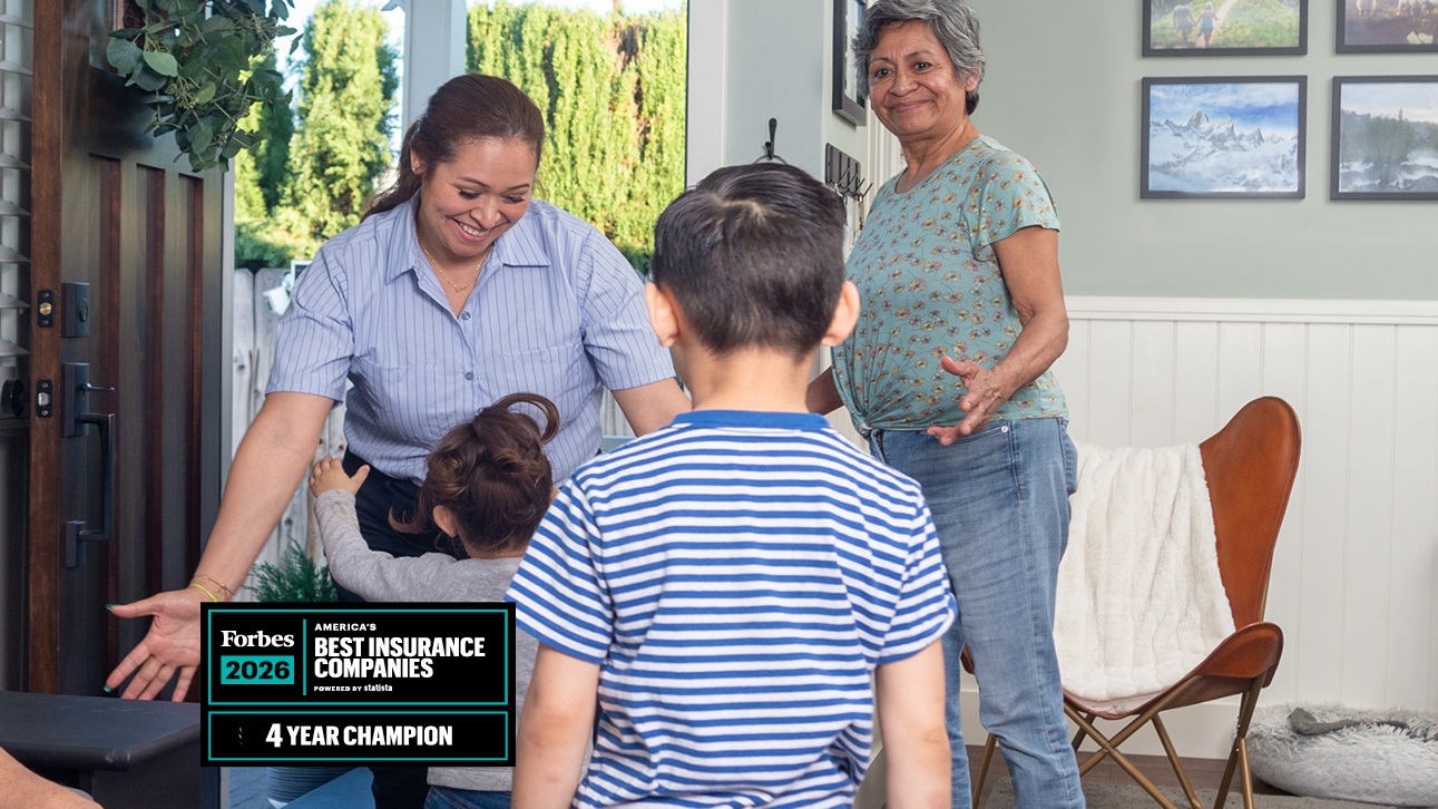 A mother is greeted by her children at the front door.
