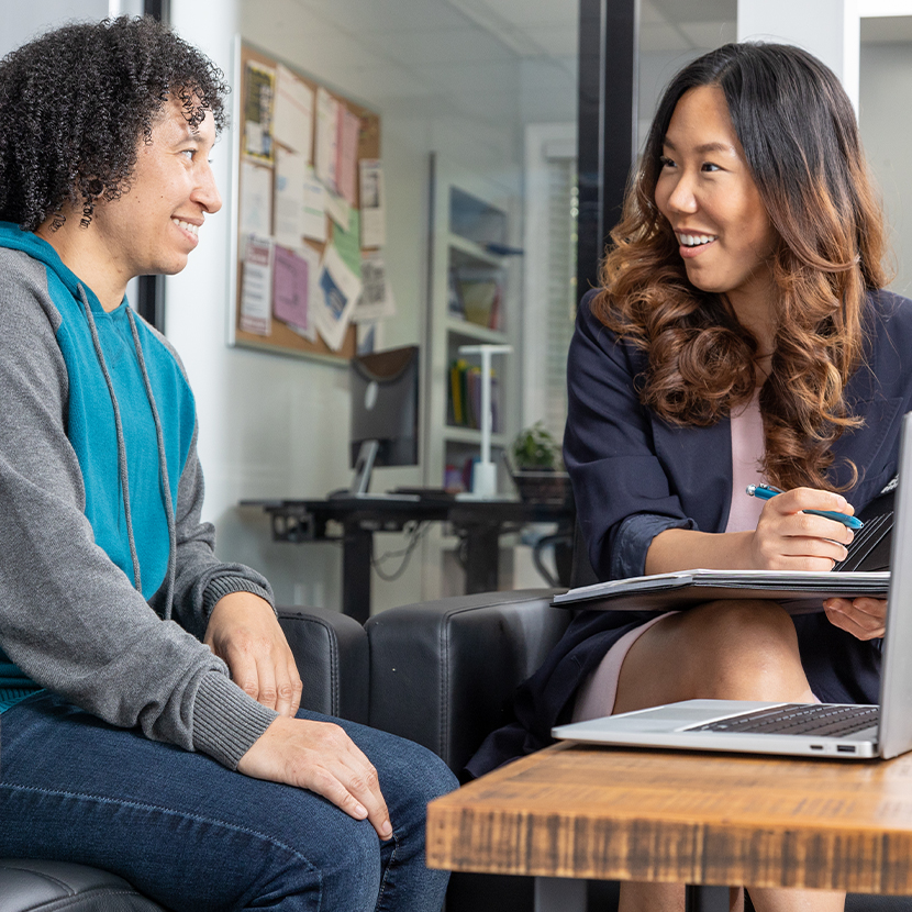 Two women talking to each other in front of a laptop