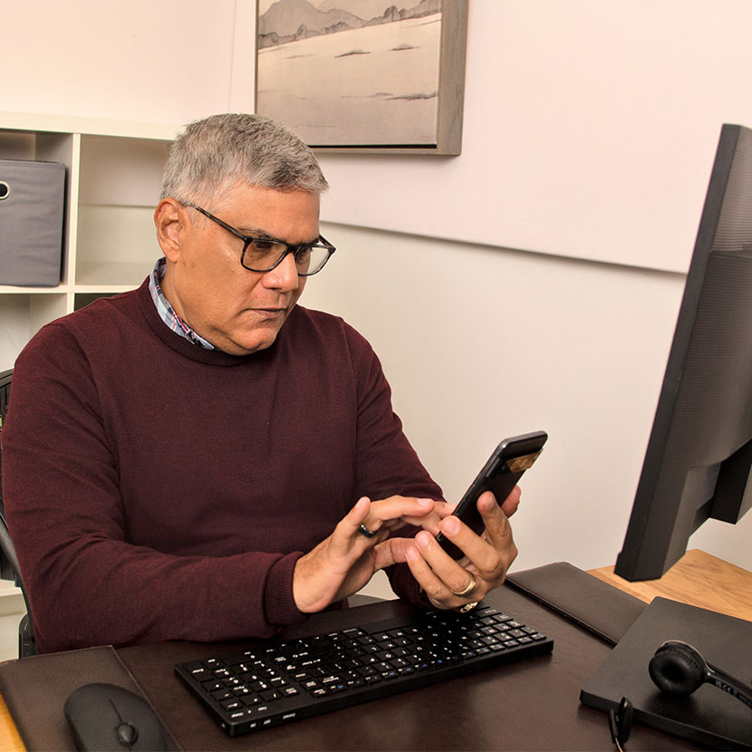 A man learns about TruStage business protection resources on his phone while sitting at his desk