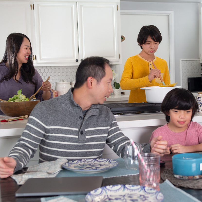 Family making dinner together and sitting at the dinner table