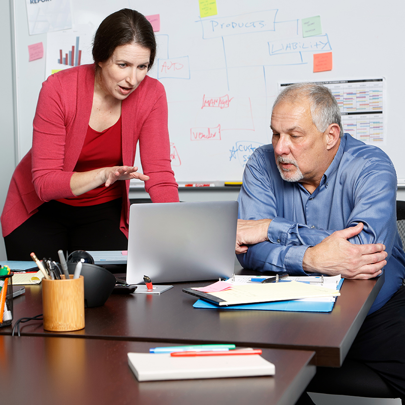 A man and woman review information on a laptop while discussing TruStage Payment Guard Insurance.