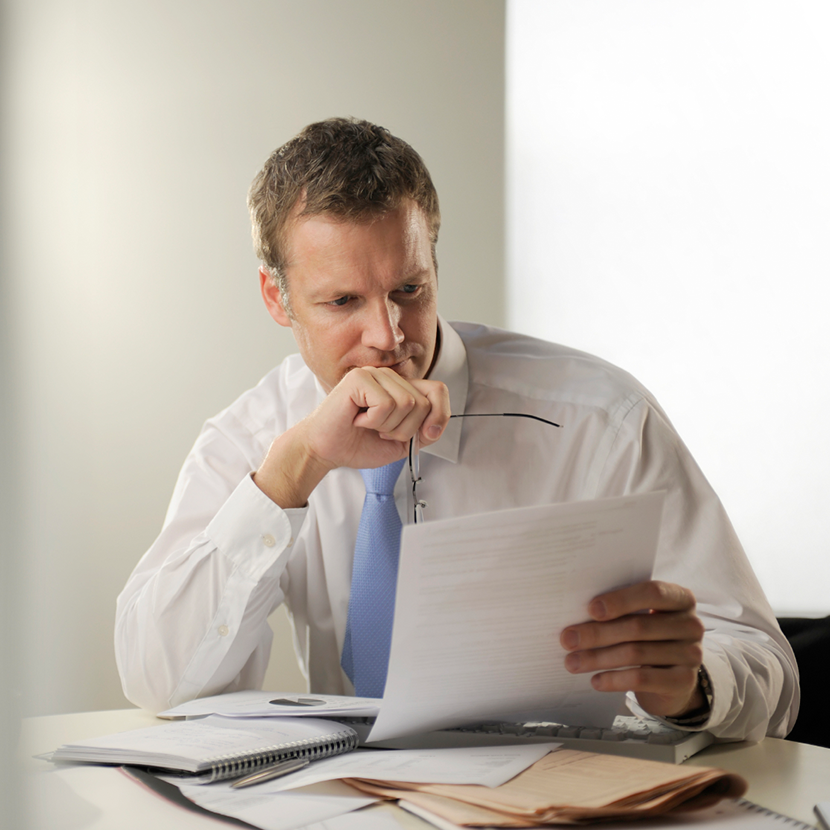 A businessman sitting at a table reviews an article to stay informed on digital lending trends.