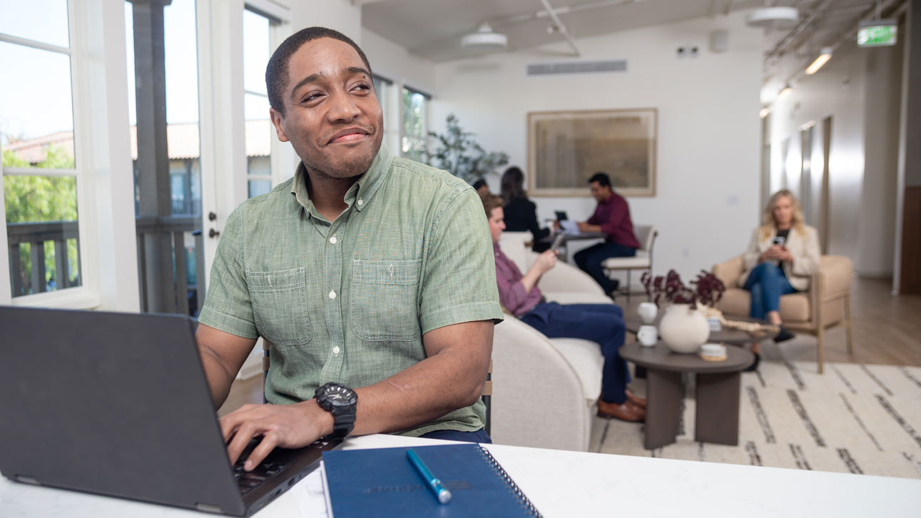 A man smiles while learning about the TruStage Discovery Conference on his laptop