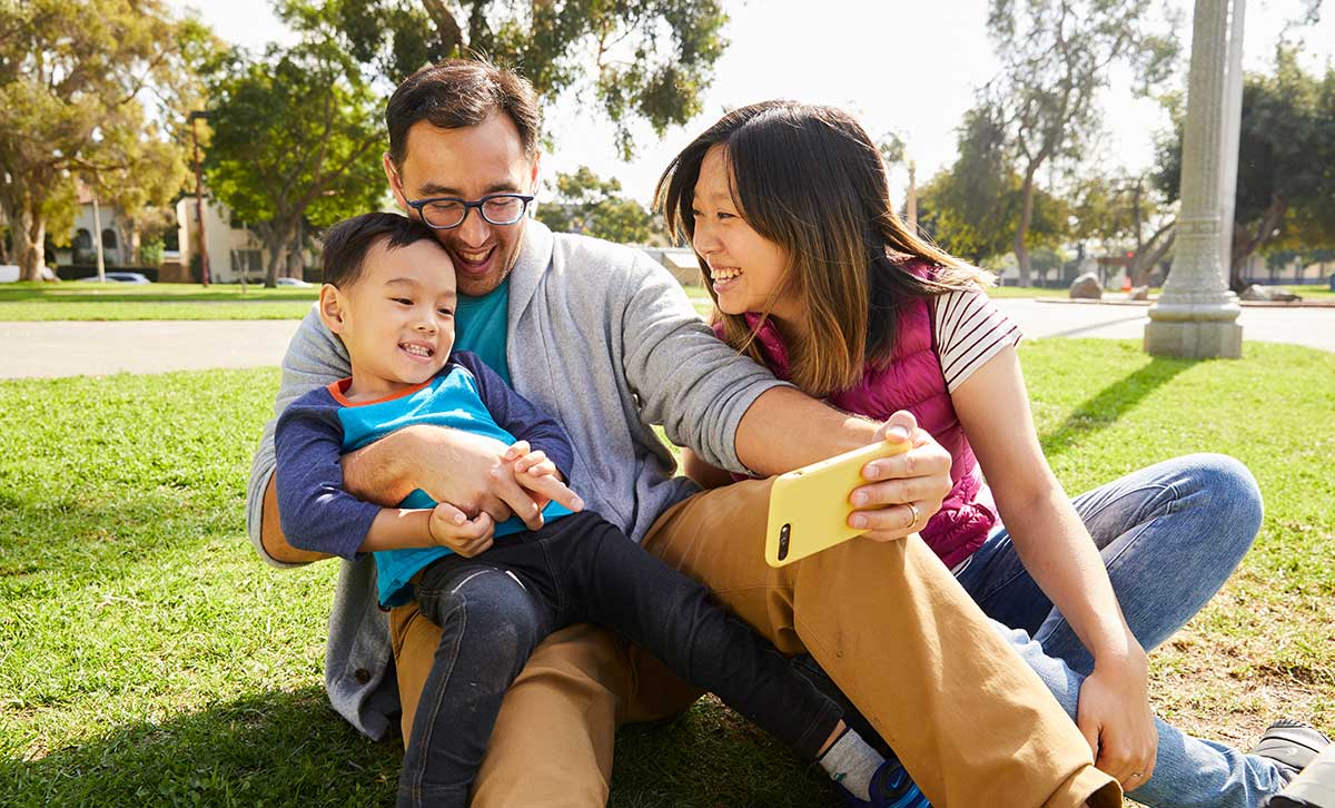 Two parents and their son take a photo outside after seamlessly applying for TruStage life insurance.