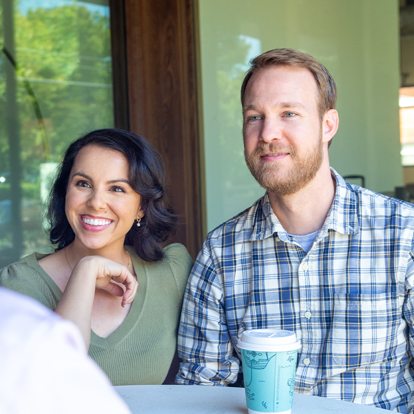 A woman and a man sit at a table smiling