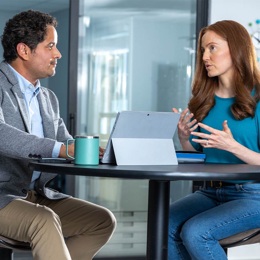 A man and woman sitting at a table talking about TruStage Payment Guard.