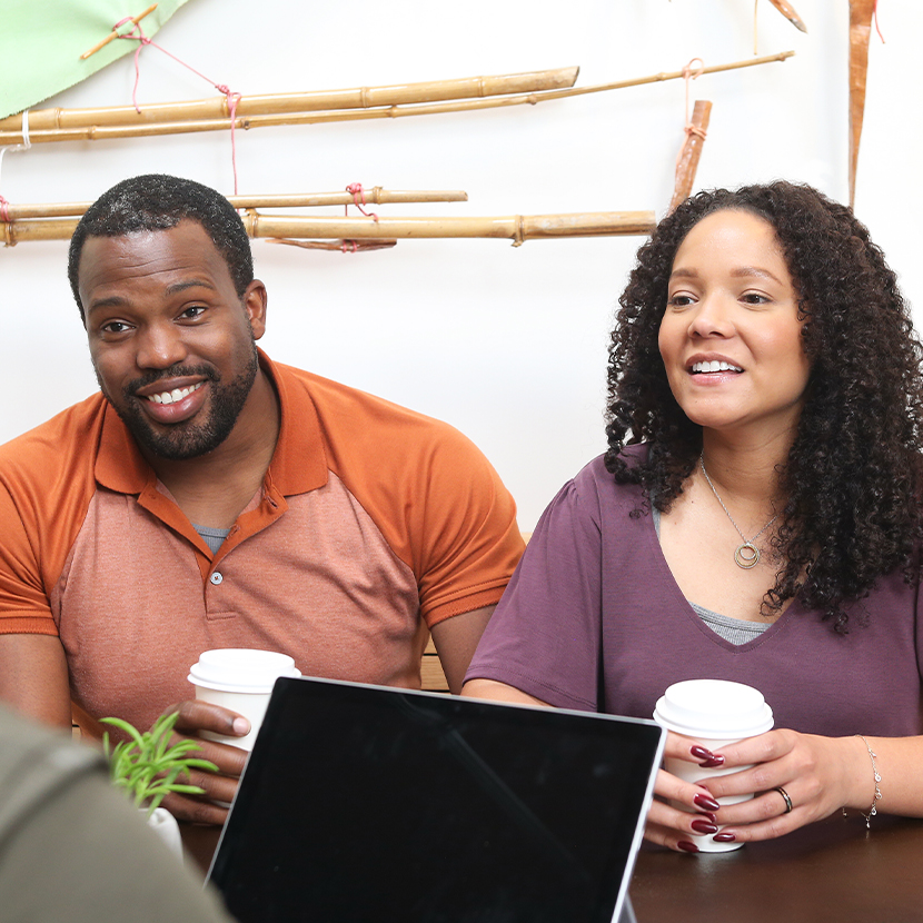 A woman and a man holding coffee cups smiling