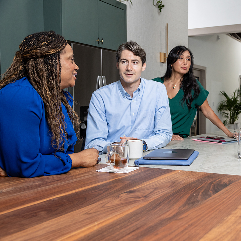 Three people standing at a table talking