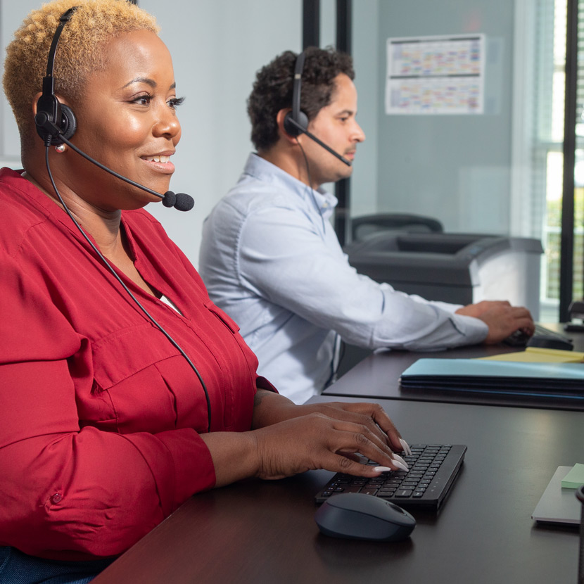 Man and woman with headsets in an office call center assisting insurance customers.