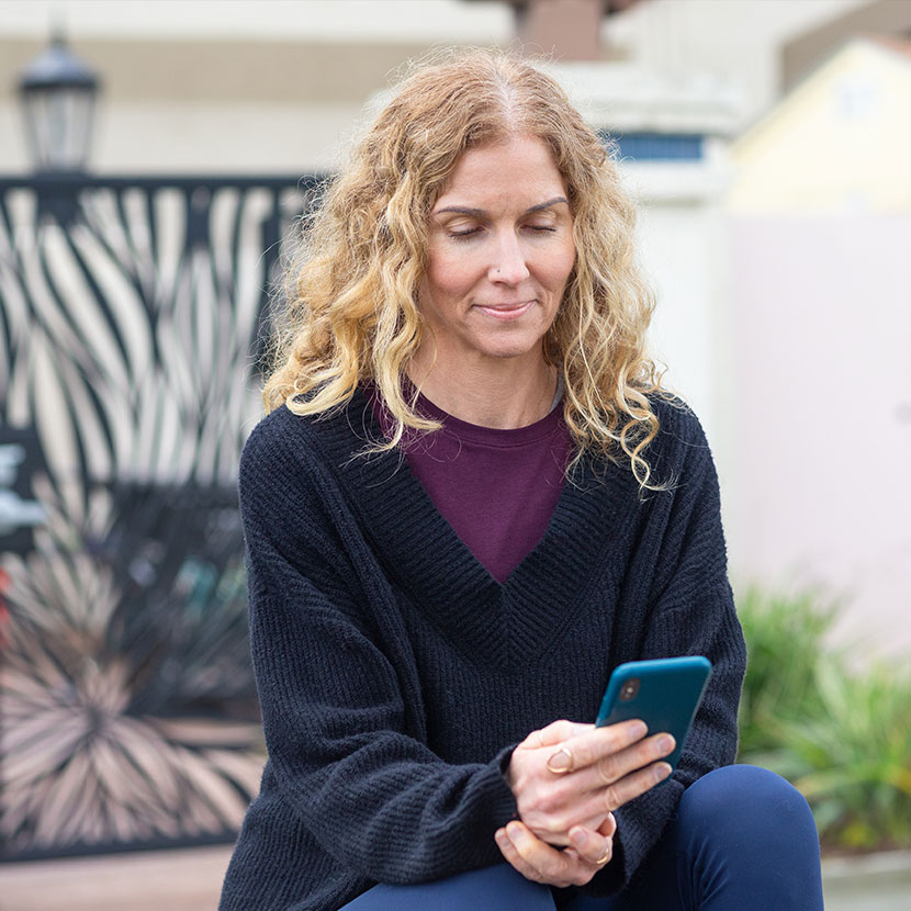 A woman on her phone reviewing the benefits of embedded life insurance.