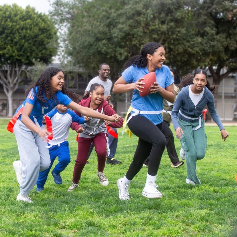 A family plays flag football in their front yard.