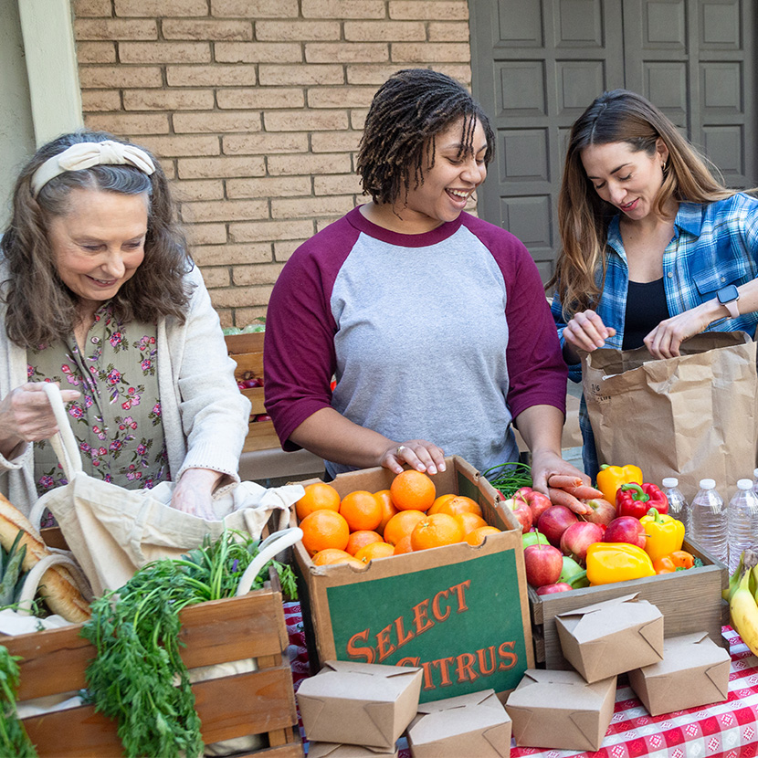 Community members exchange fresh produce while volunteering for a nonprofit organization, helping local food distribution.