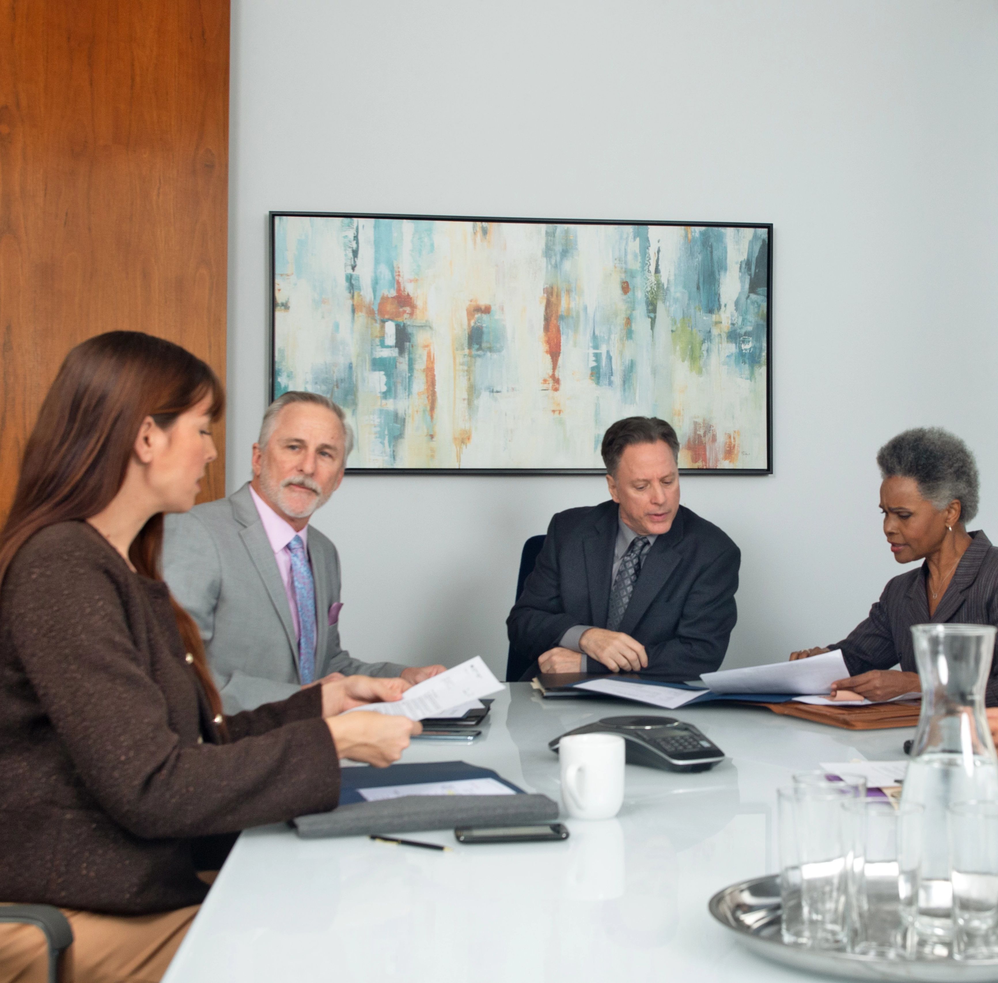 Board members sit at a desk in an office to review financial documents.