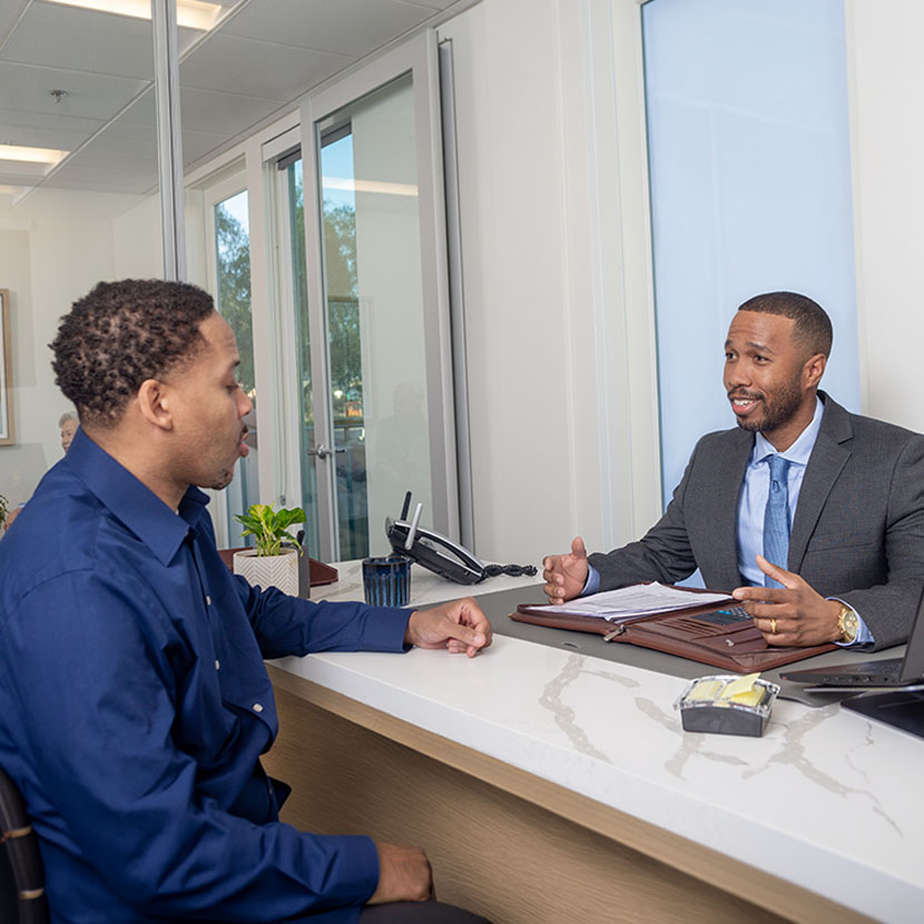A man sits at a desk with a financial professional.
