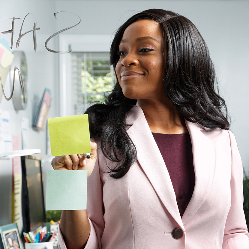 Woman in blazer smiling looking at her sticky notes