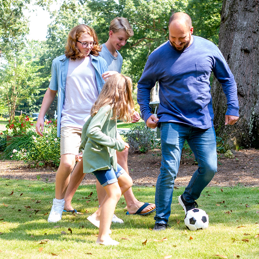 Man playing soccer with his children before they attend the Football and Finance Fair.