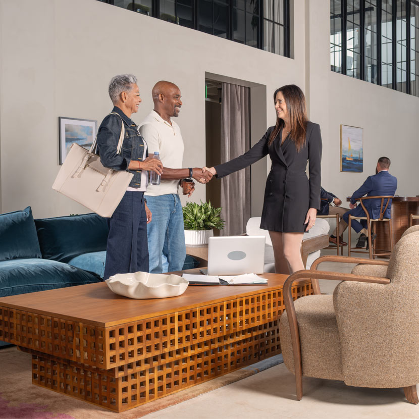 A husband and wife shake hands with a financial professional.