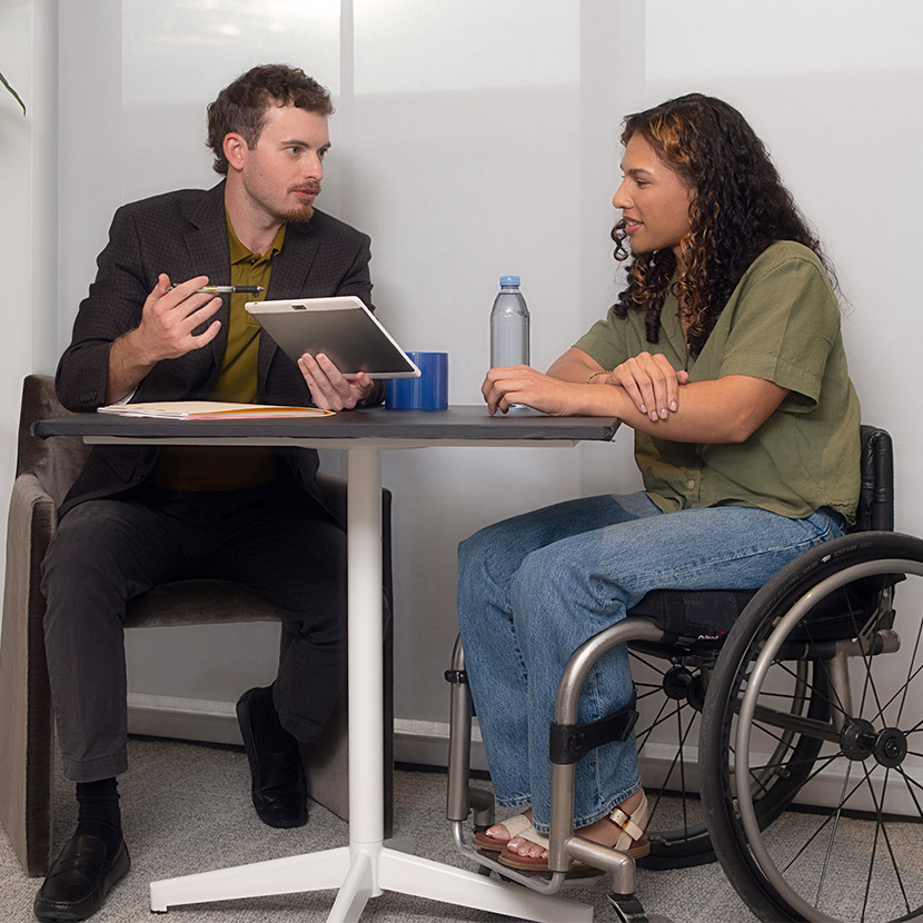 A woman sits at a desk with a financial professional.