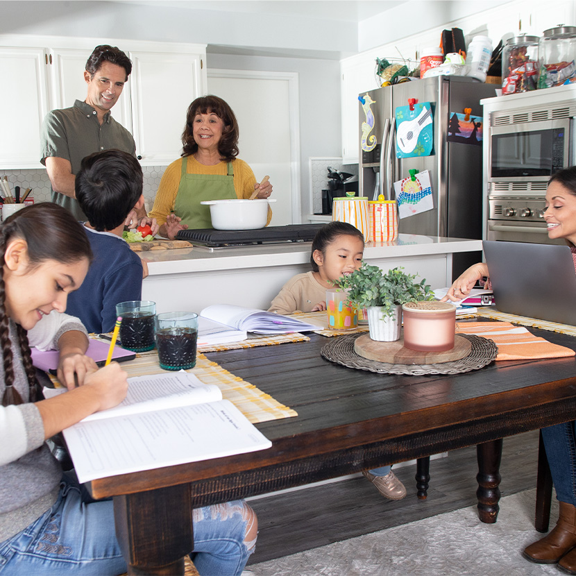 Children complete homework at the kitchen table while their parents cook and discuss findings from the new TruStage survey.