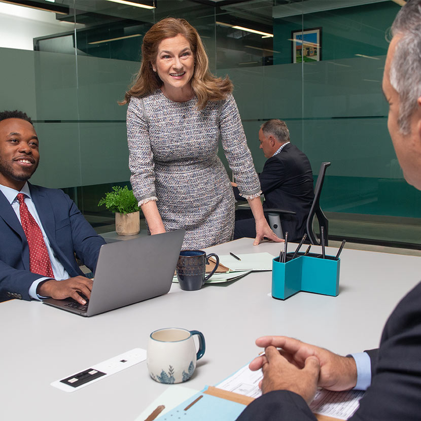 Group of people sitting around a table in an office setting talking about the TruStage Payment Guard product