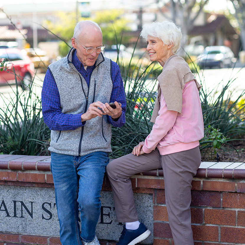 A husband and wife sit on a bench, discussing how ZoneChoice Income can help grow their guaranteed income after retirement.