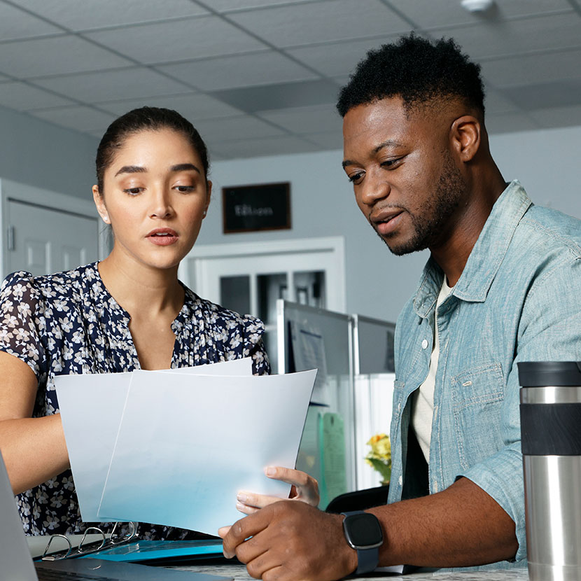 Two people review a printed copy of TruStage's blog about annuity predictions and forecast for 2025 and beyond.