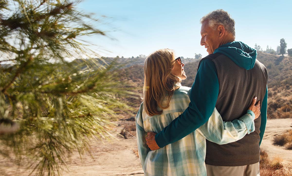 A woman and a man pause their nature hike to reflect on their finacial future that includes an annuity from TruStage.