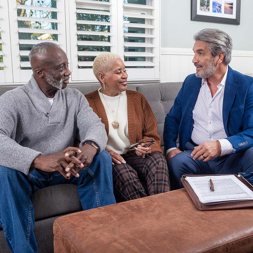 A retired African-American couple and their financial professional discuss downside protection provided by TruStage™ Annuites.