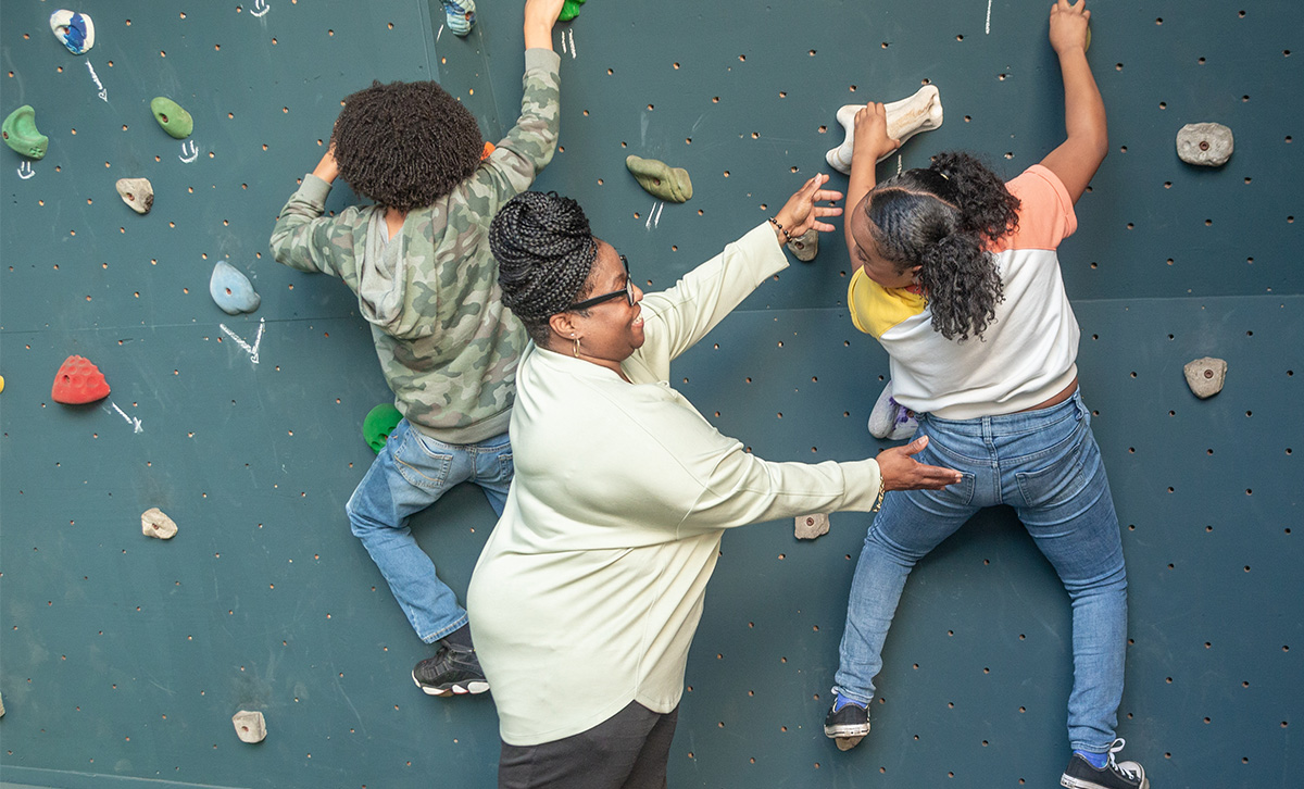 Mom helps her kids scale an indoor rock climbing wall with little care about retirement thanks to  Future Income Annuity.