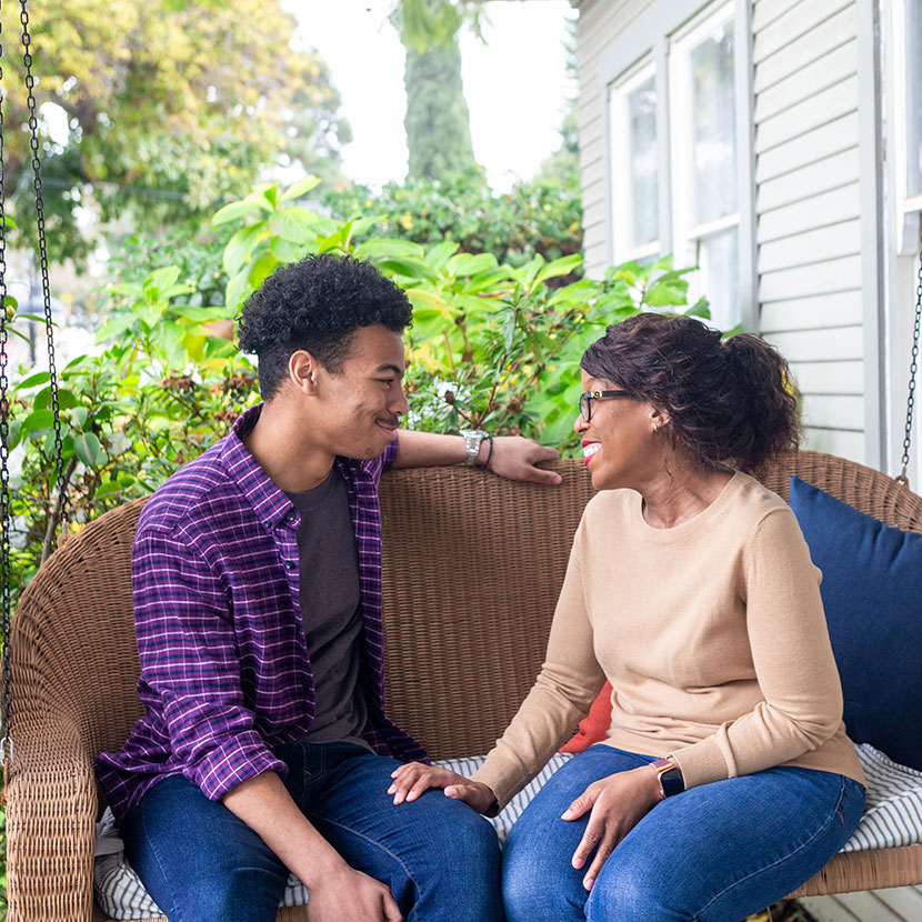 A teenager and their parent sitting on their porch