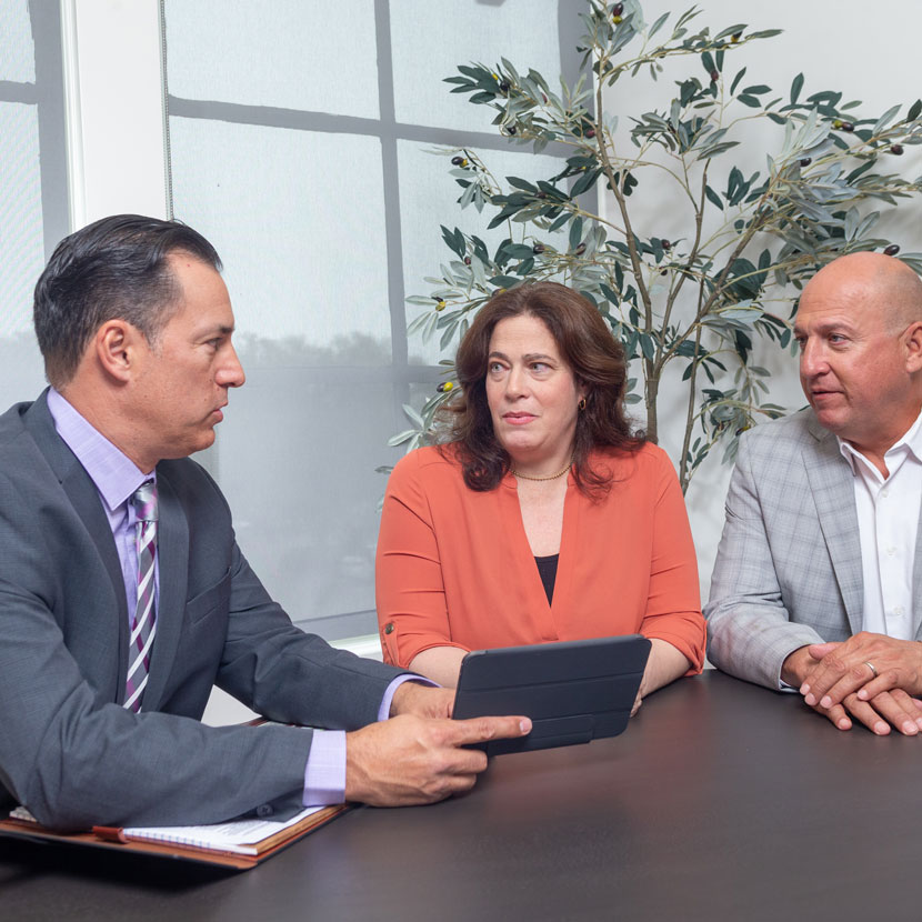 Three people sit around discussing TruStage's business protection solutions