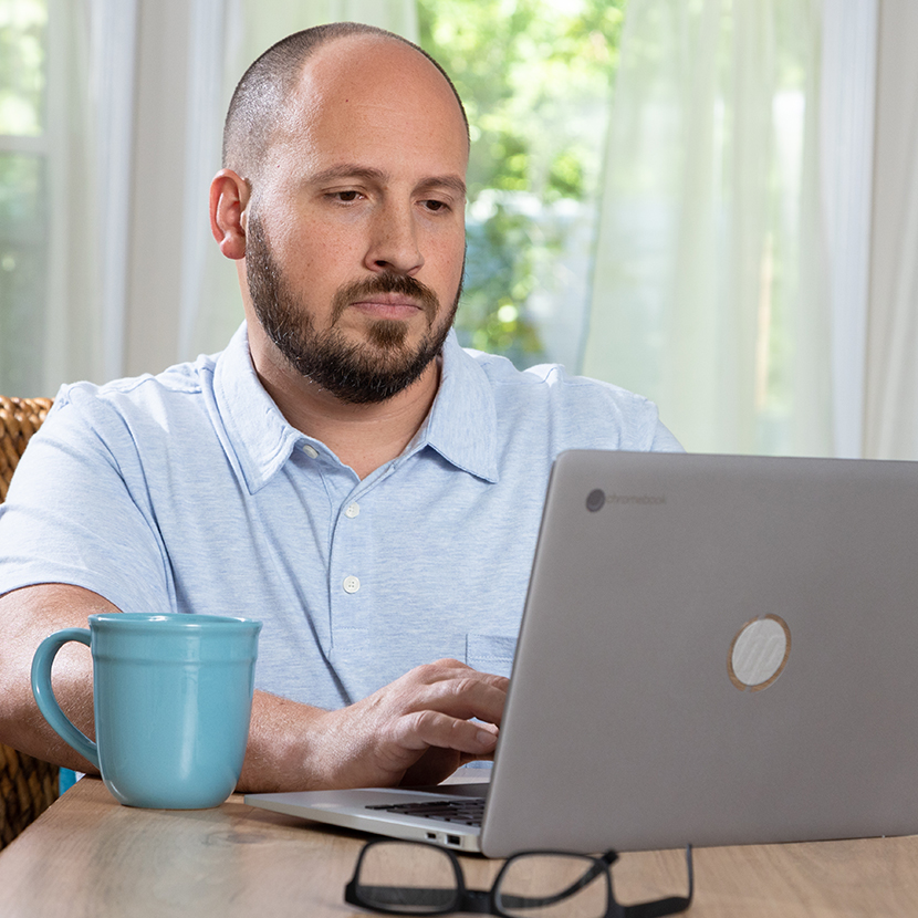 Man sitting at a desk, looking at his laptop 