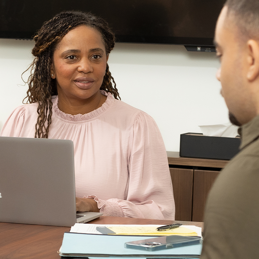 Woman and man sitting at a conference table, in an office setting, talking