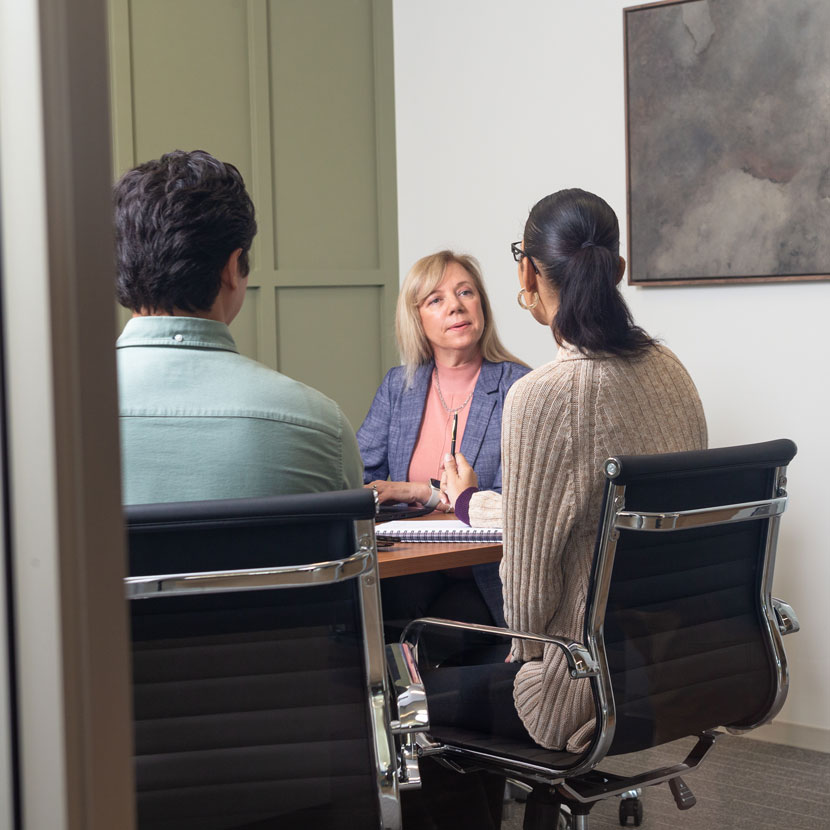 Three people sitting around a table discussing TruStage property and business liability