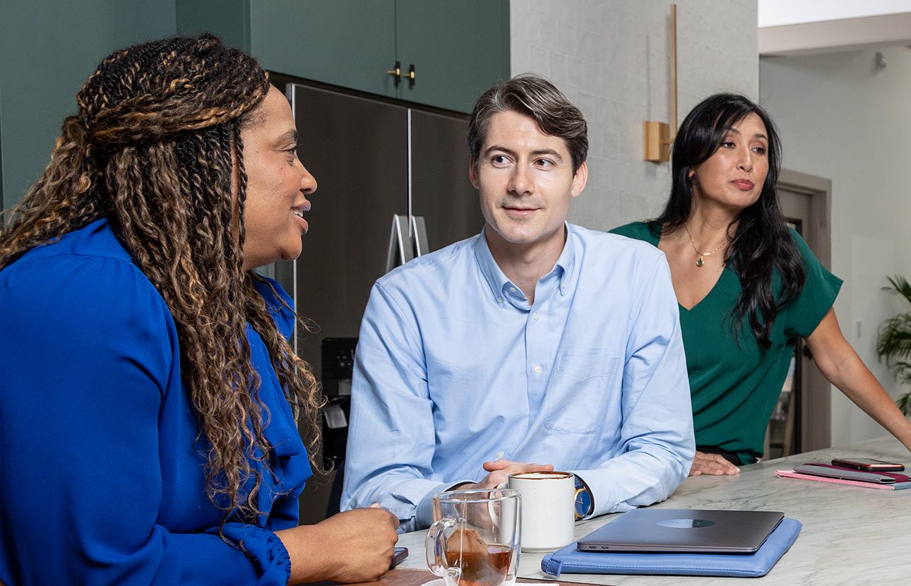 Group of people sitting at a table, in an office setting, talking