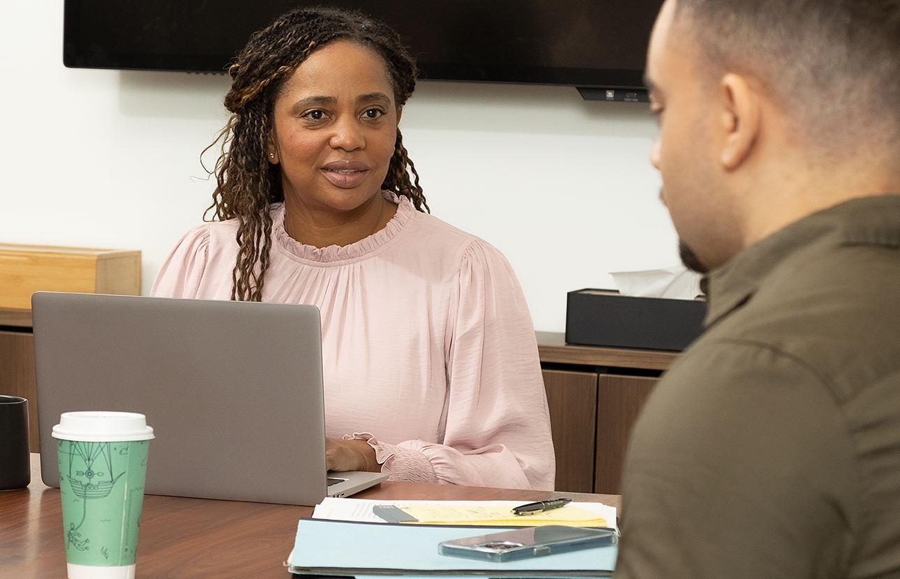 Woman and man sitting at a conference table, in an office setting, talking