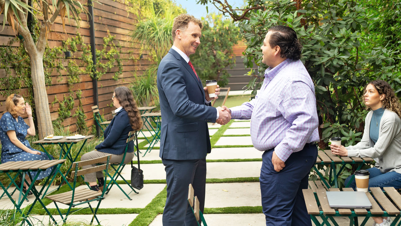 Two men shake hands discussing TruStage plastic card insurance