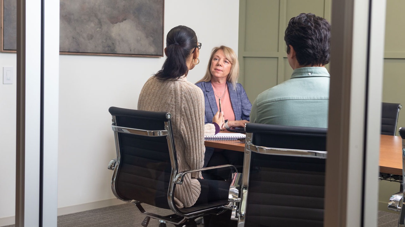Three people sitting around a table discussing TruStage property and business liability