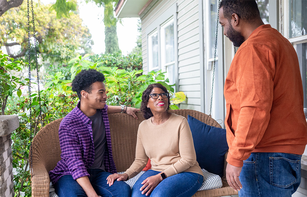 Family sits on porch of their home safeguarded by credit union real estate collateral protection.