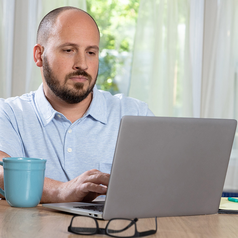 A man on a laptop reviews product offerings from his financial institution made possible through the Digital Storefront.